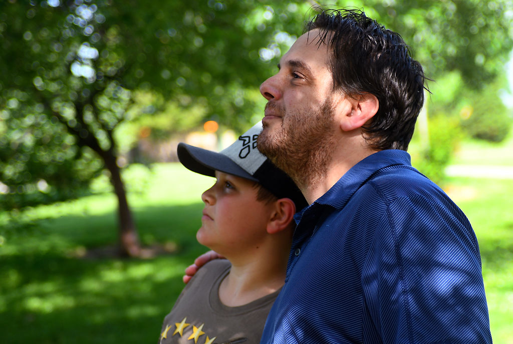 Corey Vishy and his son Landon Vishy, 13, stand together in shade on a humid and sunny Father's Day